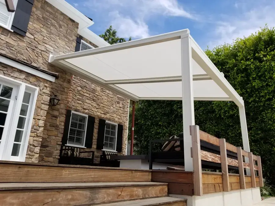 White patio roller shade installed on a structure, covering an outdoor patio.