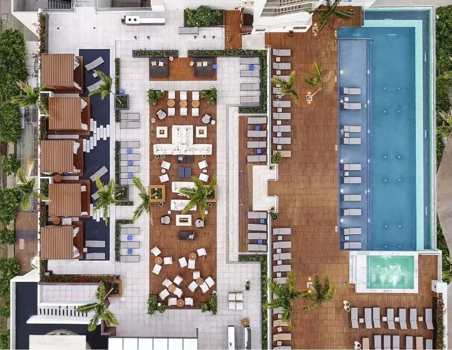 Aerial shot of a large, luxurious pool deck with wooden patios covering the furniture.