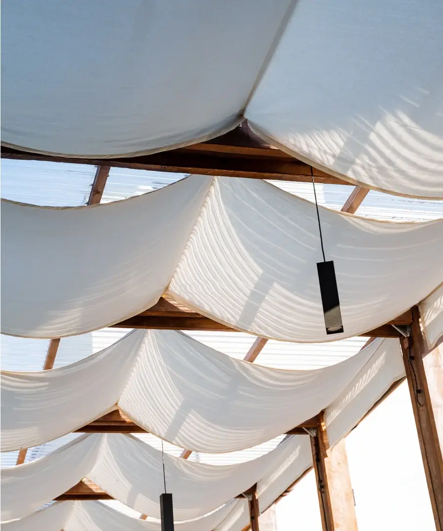 Wooden roof system with white draped shading.